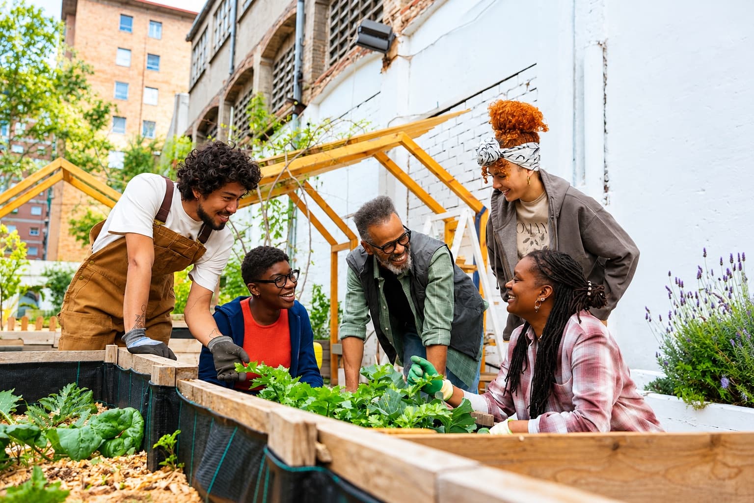 Neighbours laugh together while tending a community garden