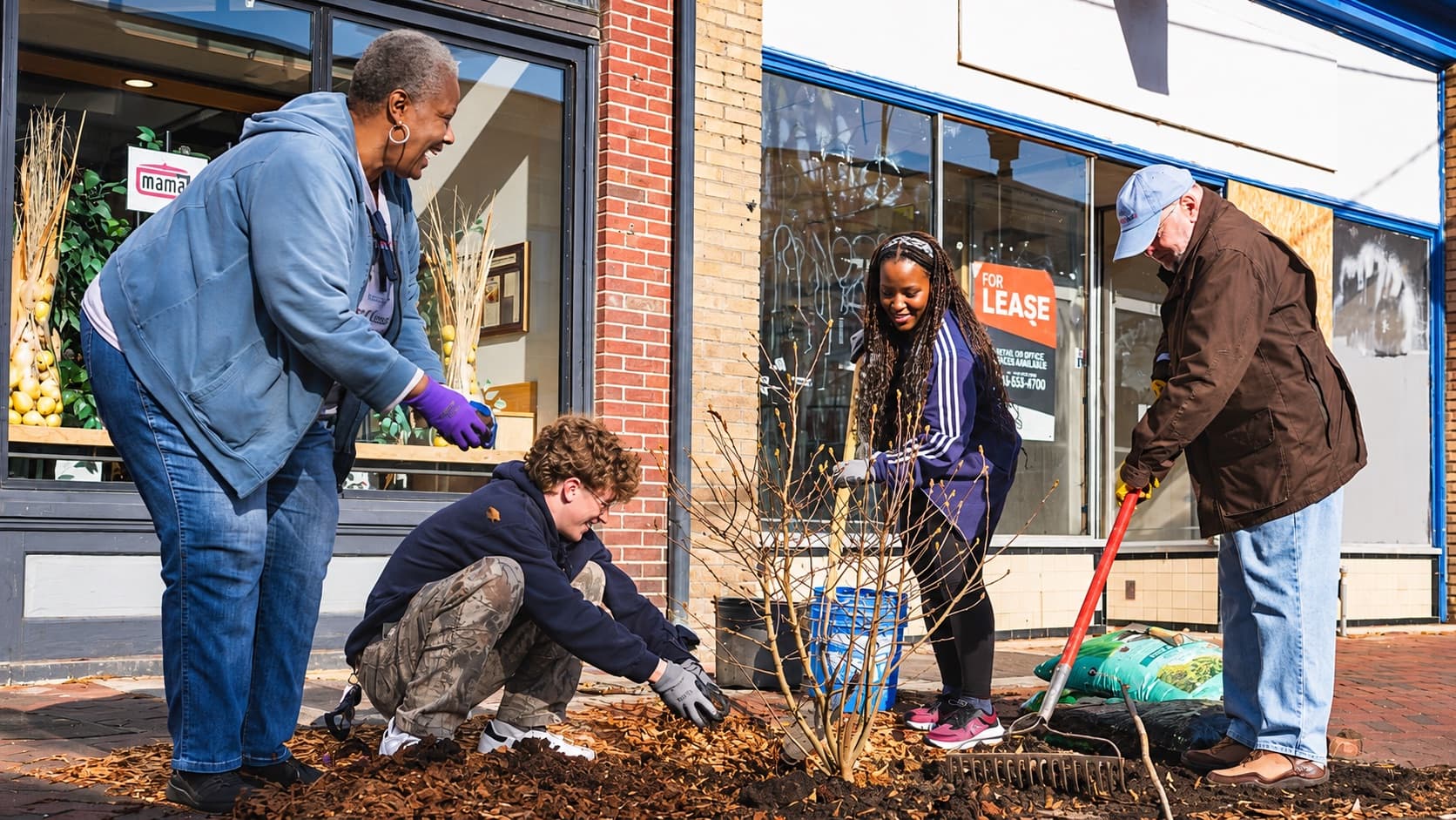Neighbours plant a shrub together outside local shops